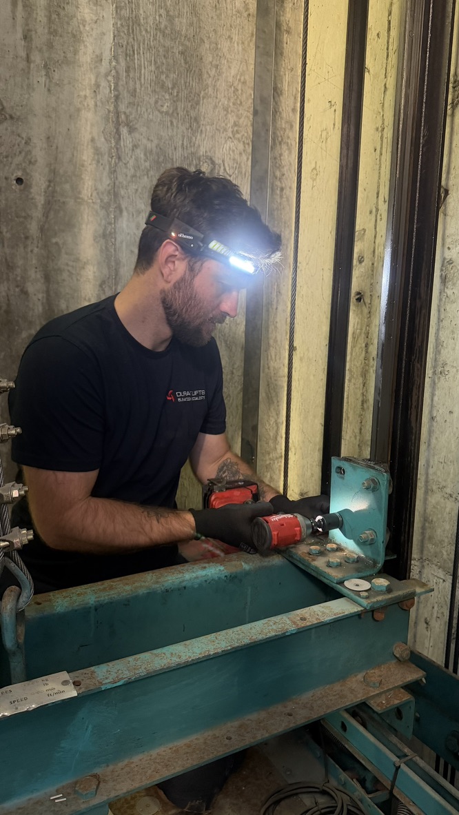 Durant Lifts engineer using a cordless tool on lift equipment inside a lift shaft